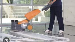 Une personne utilise un monobrosse orangée sur un sol brillant